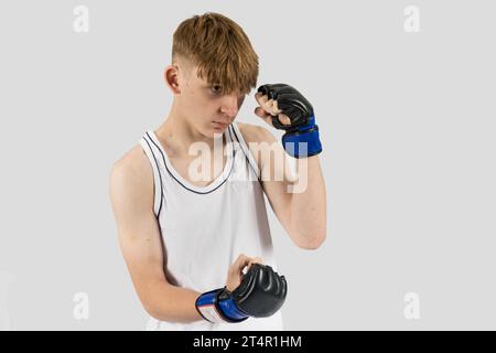 Un adolescente caucasico che indossa guanti da boxe in stile MMA Foto Stock