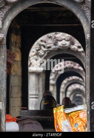 Kathmandu, Nepal: Guru indù in attesa che una famiglia prepari regali per i morti al tempio Pashupatinath, famoso tempio indù dedicato a Shiva Foto Stock
