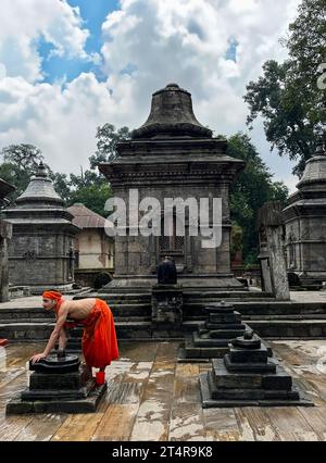 Kathmandu, Nepal: Monaco indù che pulisce gli altari dopo il sacrificio degli animali e le cerimonie di preghiera, cerimonia di cremazione al Tempio di Pashupatinath, tempio indù Foto Stock