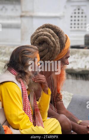 Kathmandu, Nepal: Guru indù in attesa che una famiglia prepari regali per i morti al tempio Pashupatinath, famoso tempio indù dedicato a Shiva Foto Stock