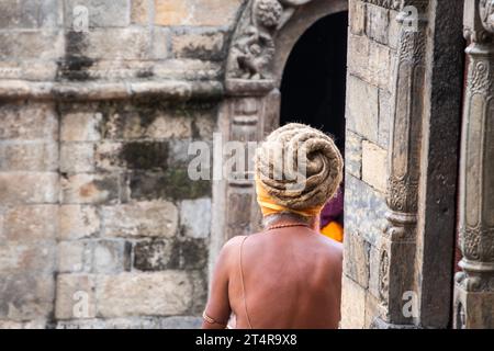 Kathmandu, Nepal: Guru indù in attesa che una famiglia prepari regali per i morti al tempio Pashupatinath, famoso tempio indù dedicato a Shiva Foto Stock