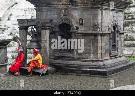 Kathmandu, Nepal: Guru indù in attesa che una famiglia prepari regali per i morti al tempio Pashupatinath, famoso tempio indù dedicato a Shiva Foto Stock
