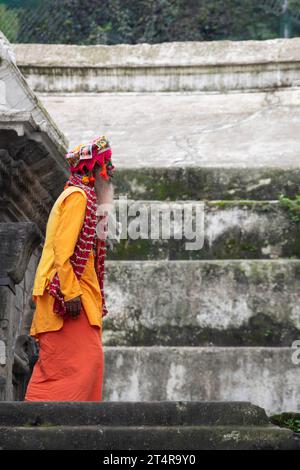 Kathmandu, Nepal: Guru indù in attesa che una famiglia prepari regali per i morti al tempio Pashupatinath, famoso tempio indù dedicato a Shiva Foto Stock