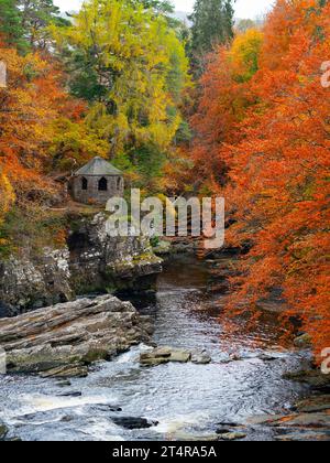 La vecchia casa estiva accanto al fiume Moriston cade con colori autunnali nel bosco di Invermoriston, Scozia, Regno Unito Foto Stock