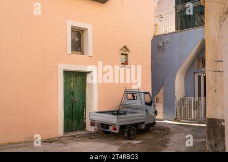 Un vecchio pick-up parcheggiato in un piccolo vicolo tra edifici color pastello in una giornata di sole Foto Stock