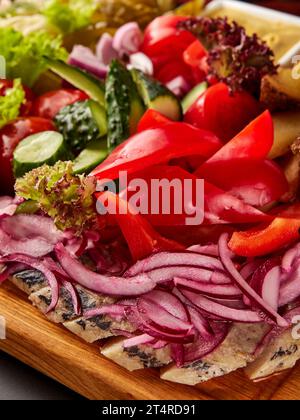 Aringhe a fette servite con verdure fresche assortite e insalata su tagliere di legno. Foto Stock