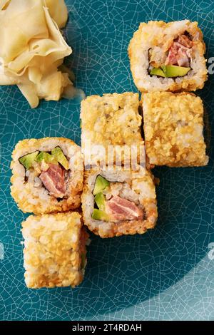 Sushi fritto caldo con tonno e avocado su piatto di ceramica blu. Foto Stock