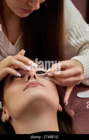 preparare il nastro adesivo in cotone sotto gli occhi prima della procedura di estensione delle ciglia Foto Stock