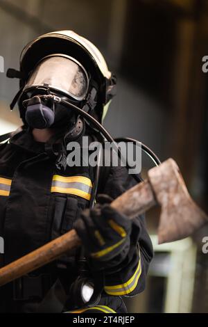 Ritratto femminile del pompiere con equipaggiamento completo con maschera di ossigeno e ascia. Foto Stock