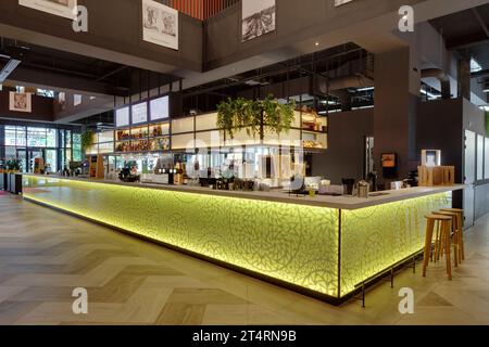 Bancone della barra nell'atrio, con pannello in vetro giallo retroilluminato. Theater Zuidplein, Rotterdam, Rotterdam, Paesi Bassi. Architetto: De Zwarte Hond, 2020. Foto Stock