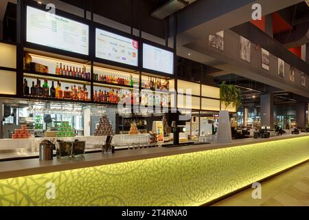 Bancone del bar nell'atrio, con pannello in vetro giallo retroilluminato, con balcone dell'atrio. Theater Zuidplein, Rotterdam, Rotterdam, Paesi Bassi. Architetto: De Zwar Foto Stock