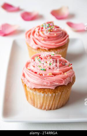 Cupcake alla crema di burro alla vaniglia con glassa rosa e spruzzi Foto Stock