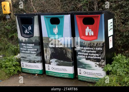 Tre coloratissimi contenitori per il riciclaggio dei rifiuti di cani in busta, lattine e cartoni di plastica mista lungo il sentiero costiero del Pembrokeshire National Park West Wale Foto Stock