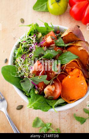 Insalata vegetariana sana con pomodori cimeli, patate dolci e germogli crudi fatti dall'alto. Foto Stock