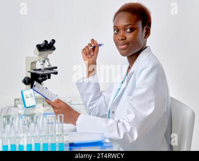 Una scienziata africana o una studentessa laureata in camice da laboratorio guarda la macchina fotografica Foto Stock