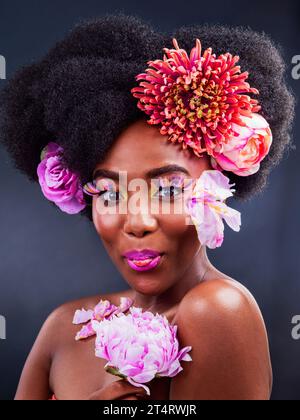 Perché inserirsi quando il trucco può farti risaltare. Foto in studio di una bella giovane donna che posa con dei fiori nei capelli. Foto Stock