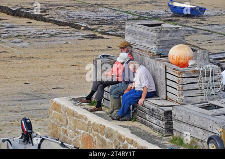 Tre vecchi signori, mentre erano in viaggio per una luminosa giornata autunnale che metteva il mondo al sicuro, sedevano su casse che si affacciavano sulla spiaggia del porto di Hugh Town, a St. Marys, io Foto Stock