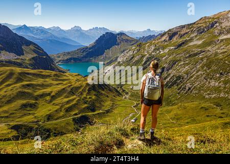 eine junge Frau steht an einem Wanderweg auf einem Berg und schaut auf den Spullersee a Vorarlberg Lech Östereich Foto Stock