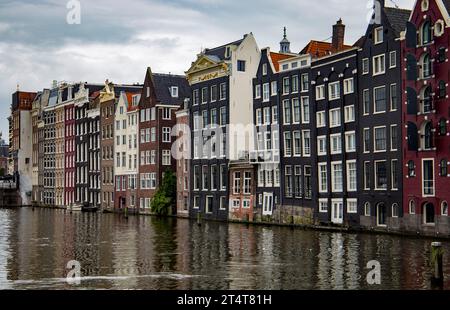 Storiche case sui canali lungo l'acqua di Amsterdam sotto un cielo nuvoloso Foto Stock