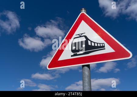 Cartello di attraversamento ferroviario triangolare con cielo nuvoloso blu sullo sfondo Foto Stock