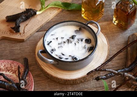 Preparazione di unguento di radice mista da piante fresche e lardo di maiale fuso Foto Stock