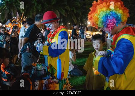 Bangkok, Thailandia. 31 ottobre 2023. I clown offrono palloncini ai bambini durante l'Happy Halloween Festival 2023 alla Jodd Fairs DanNeramit, a Bangkok. Il più famoso mercato notturno di Bangkok, Jodd Fairs, ha recentemente aperto una nuova filiale al DanNeramit, un formale parco a tema con un castello da favola che copre un'area di 52800 metri quadrati con una varietà di bancarelle come vestiti e accessori, oggetti d'epoca, birre artigianali, souvenir, cibo tailandese e internazionale. Credito: SOPA Images Limited/Alamy Live News Foto Stock