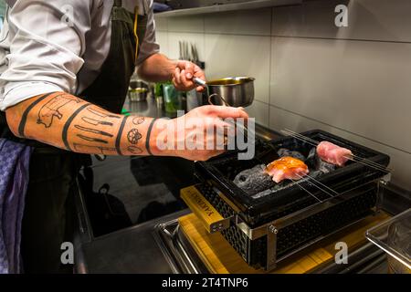 Lo chef Ingo Mark griglia il filetto di carpa su una griglia giapponese al coperto su carbone di legna di lychee. Wiesau (VGem), Germania Foto Stock