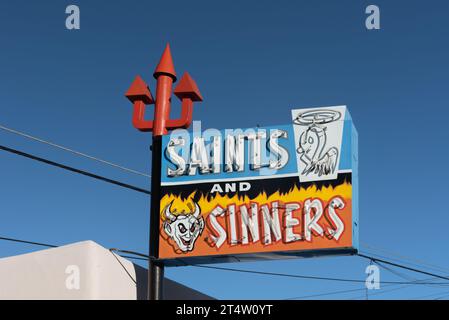 Insegna al neon dai colori vivaci con tridente rosso per Saints and Sinners, negozio di liquori fondato nel 1963, Espanola, New Mexico, Stati Uniti, Stati Uniti. Foto Stock