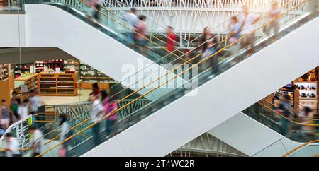 Persone su molte scale mobili veloci in un moderno centro commerciale Foto Stock