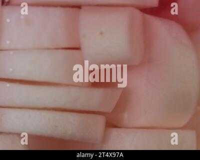 Primo piano di dischi Daikon Radish sottaceto o fette di liquido in un vaso di vetro, rosa pallido da fette di barbabietole, gusto dolce e piccante di crostata Foto Stock