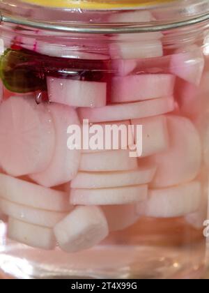 Un barattolo di Daikon bianco sottaceto fatto in casa si irradia pronto a mangiare, con una fetta di barbabietola di colore rosa, peperoncino per sapore, dolce piccante e sapore croccante Foto Stock