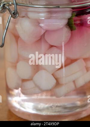 Daikon sottaceto si irradia in un vaso di vetro con una fetta di barbabietola Foto Stock