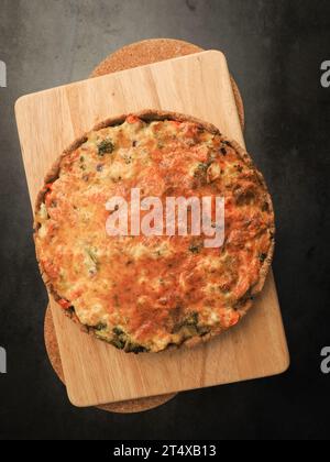 Gustosa quiche di verdure biologiche su un tagliere in cucina, alimentazione sana o concetto di dieta, cibo vegetariano Foto Stock