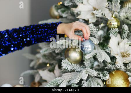 Decorare l'albero di Natale, tenendo in mano il giocattolo di Natale. Vacanze, Natale e Capodanno Foto Stock
