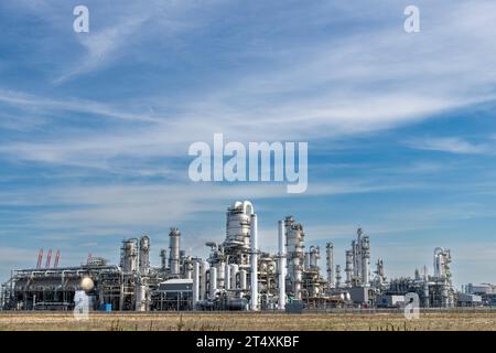 Vista panoramica di un impianto chimico o di una raffineria con torri di frazionamento o di distillazione, caldaie e tubi per petrolio e prodotti chimici contro un cielo blu Foto Stock