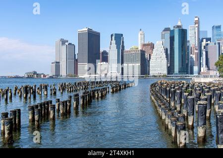 Centinaia di vecchi sostegni in legno nell'East River con vista panoramica sui grattacieli e i monumenti storici di Lower Manhattan, New York City, NY, USA aga Foto Stock