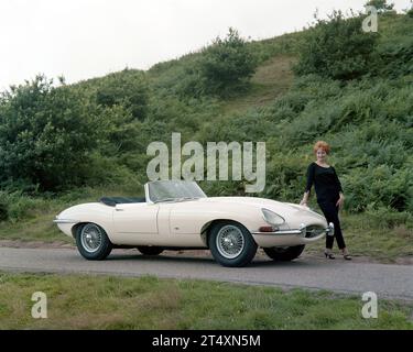 Foto pubblicitaria iniziale di Jaguar e-TYPE S1, Open a due posti, 3,8L, con modello in pantaloni neri e maglione nero. Preso all'Halesowen Golf Club sulla 21 Foto Stock