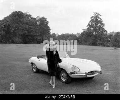 Foto pubblicitaria in bianco e nero di Jaguar e-TYPE S1, Open a due posti, 3,8L con modello femminile in pelliccia nera all'Halesowen Golf Club il 21/8/1961 Foto Stock