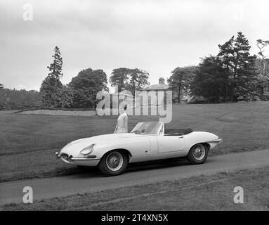 Foto pubblicitaria in bianco e nero di Jaguar e-TYPE S1, Open a due posti, 3,8L, con modello femminile in abito bianco all'Halesowen Golf Club il 21/8/1961. Foto Stock