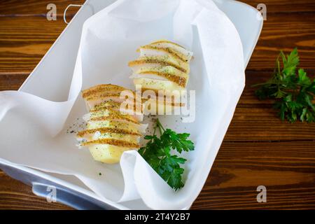 Patate crude ripiene di strutto e spezie, preparate per cuocere in carta da forno. Foto Stock