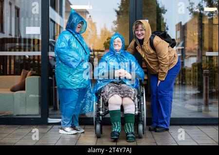 Ritratto di famiglia di una donna di 41 anni con sindrome di Down, una nonna su una sedia a rotelle e una donna di 37 anni che indossa abiti impermeabili, Tienen, Belgio Foto Stock