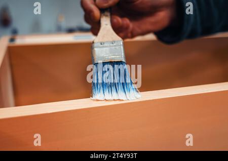 La spazzola applica la vernice sui mobili. Verniciare mobili con vernice Foto Stock