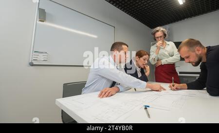 L'estrusione femminile valuta il lavoro dei subordinati. Progettisti ingegneri a una riunione. Foto Stock