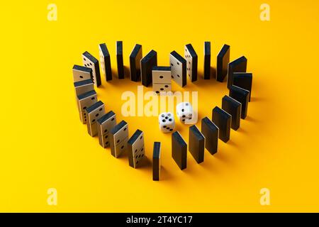 Le tessere Domino sono impostate a forma di cuore sulla vista superiore dello sfondo giallo Foto Stock