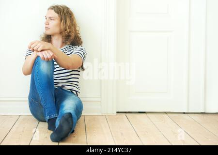 Uomo, pensiero e moda per stare seduti a terra in casa per cercare, guardare o riposare. Svezia ragazzo, uomo e solo con idea per il futuro da Foto Stock