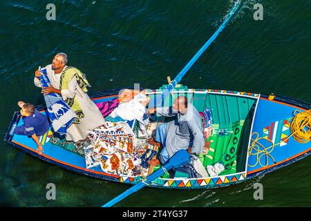 I venditori di tessuti sulle loro barche si avvicinano a una nave da crociera in attesa di entrare nella chiusa di Esna. I venditori sperano di vendere beni ai turisti. Esna, Egitto – 20 ottobre Foto Stock