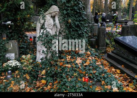 La vecchia scultura in pietra tombale e le candele sono visibili nel cimitero nel giorno di tutti i Santi al Cimitero Evangelico-Augusta a Varsavia. Giorno di Ognissanti (o Dzie? Zaduszny in polacco) è un giorno festivo in Polonia. E' un'occasione per ricordare i parenti deceduti. In questo giorno, la gente porta fiori, tipicamente crisantemi, e candele nei cimiteri. L'intero cimitero è pieno di luci nell'oscurità. Il cimitero evangelico-Augusta è uno storico cimitero protestante luterano situato nella parte occidentale di Varsavia. Dalla sua apertura nel 1792, più di 100.000 persone sono state sepolte lì. Foto Stock