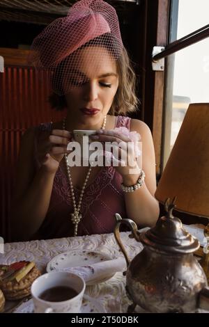 Scena di rievocazione di una donna di vestito flapper 1920s godendo di tè in un autentico compartimento del treno a vapore 1927 Foto Stock