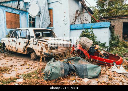 Campagna. Un'auto nel cortile di una casa, danneggiata dai bombardamenti dell'artiglieria. Guerra in Ucraina. Invasione russa dell'Ucraina. Terrore per i civili Foto Stock
