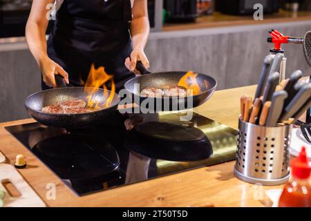 Hamburger di carne o tortino a forma di cotoletta che vengono fritti poco a poco in olio su una padella Foto Stock